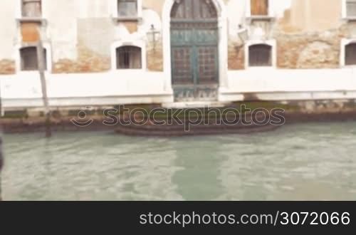 Steadicam shot of a woman standing by the canal in Venice and using retro camera to take photos of aged houses