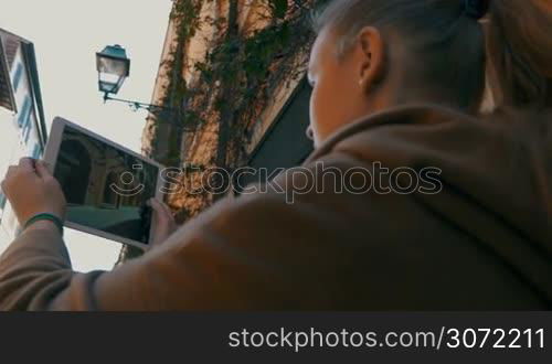 Steadicam shot of a woman using tablet computer to take photos of ancient street and building in Rome