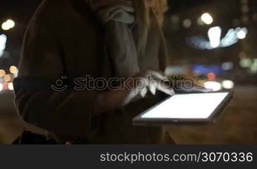 Steadicam shot of a woman using touch pad while walking outdoor in the evening
