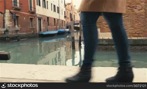 Steadicam shot of a woman walking along the canal in Venice, Italy. Only feet can be seen