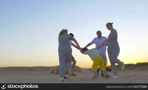 Steadicam shot of members of a big family joining hands and dancing in circle.