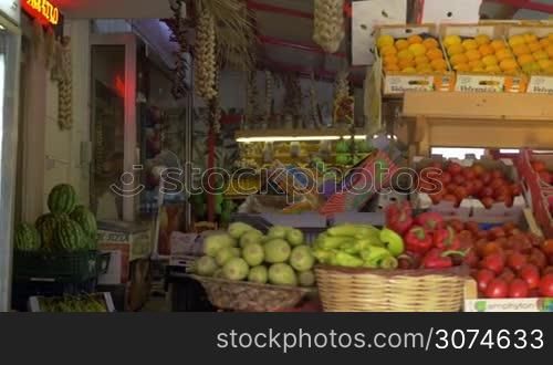 Steadicam shot of passing by the counter with fresh fruit and vegetables in street market