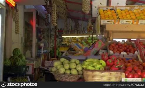 Steadicam shot of passing by the counter with fresh fruit and vegetables in street market
