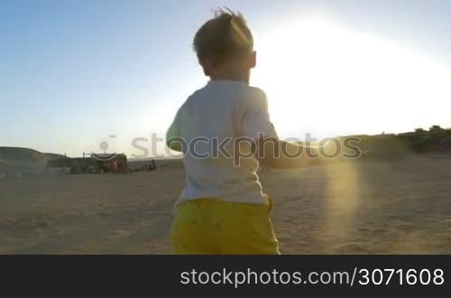 Steadicam slow motion shot of a boy running to his parents. They take him in arms, hug and kiss him.