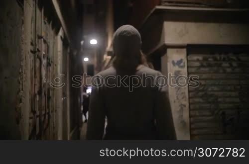 Steadicam slow motion shot of a young woman walking along the narrow street of an old town. She&acute;s lifting her head to view buildings around her.