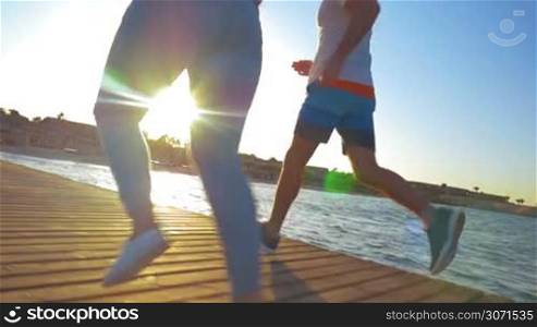 Steadicam slow motion shot of legs of athletic couple went for a run in the morning.