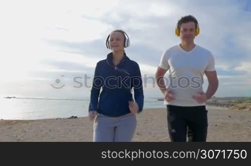 Steadicam slow motion shot of man and woman running towards the camera. They are smiling and feel themselves good.