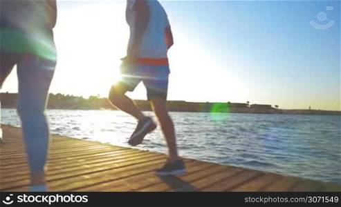 Steadicam slow motion shot of two athletic people jogging in the morning. They are well-lit with rising sun.