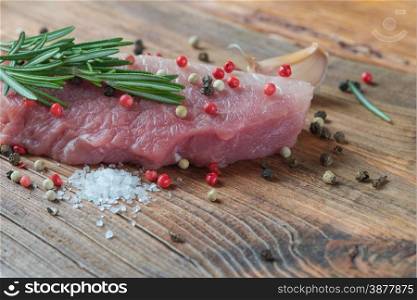Steak from fresh organic meat and sprig of rosemary on an old wooden board close up