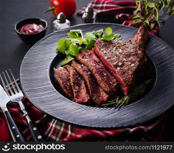 Steak on the bone. Rib eye. Tomahawk steak on the black plate with rosemary. Roasting - Rare. Entrecote.