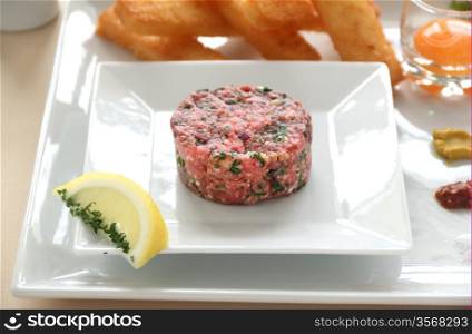 Steak tartare with raw egg in a glass ready to add to the beef.