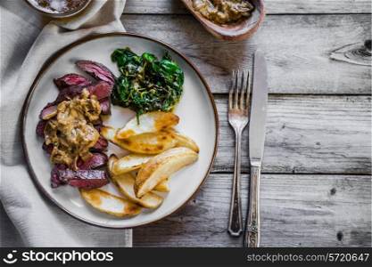 Steak with baked botatoes and green salad on wooden background