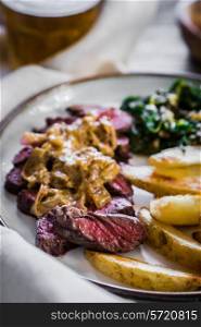 Steak with baked botatoes and green salad on wooden background
