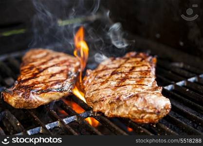 Steaks on barbecue. Beef steaks cooking in open flame on barbecue grill