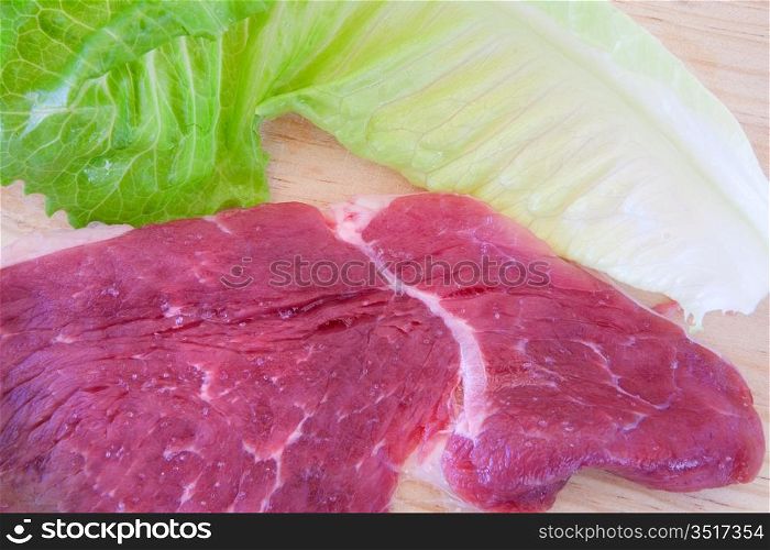 Steaks raw pork and lettuce on cutting board