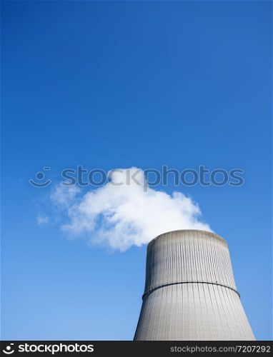 steam and blue sky above large chimney of nuclear power plant near german town lingen in lower saxony