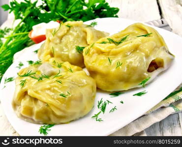 Steam meat pies and potatoes, dill in a dish on a kitchen towel, cream sauce, parsley on a wooden boards background