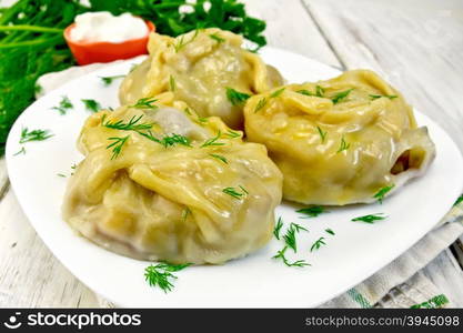 Steam meat pies and potatoes, dill in a white plate on a kitchen towel, cream sauce, parsley on a wooden boards background