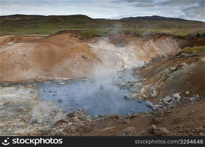Steam rising from rocky geothermal pool