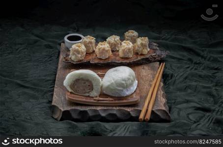 Steamed buns with minced pork filling and Pork shumai or Chinese steamed dumpling served with sour sauce and wooden chopstick. Chinese Dim Sum. Space for text, Selective Focus.