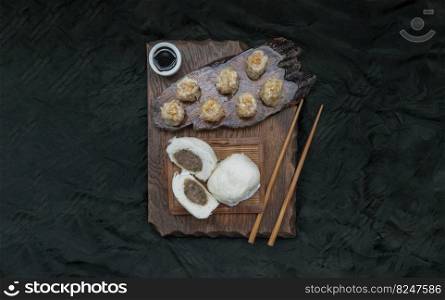Steamed buns with minced pork filling and Pork shumai or Chinese steamed dumpling served with sour sauce and wooden chopstick. Chinese Dim Sum. Top view, Space for text, Selective Focus.
