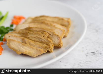 Steamed chicken breast on a white plate with spring onions and chopped carrots. Selective focus.