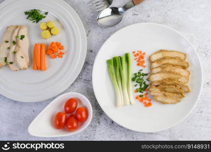 Steamed chicken breast on a white plate with spring onions and chopped carrots. Selective focus.