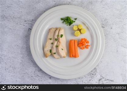 Steamed chicken breast on a white plate with spring onions and chopped carrots. Selective focus.