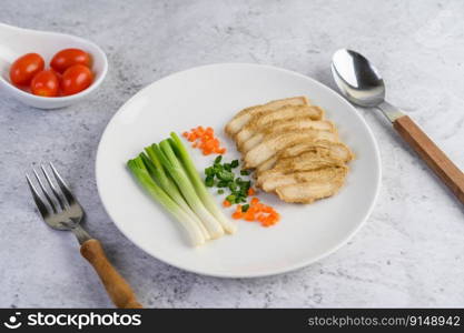 Steamed chicken breast on a white plate with spring onions and chopped carrots. Selective focus.