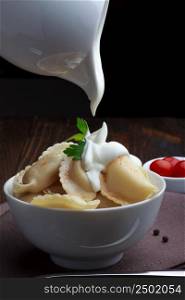 Steamed meat dumplings, pouring sour cream, traditional pelmeni or varenyky dish
