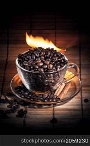 Steaming cup of coffee, cinnamon sticks and a coffee beans on fire. Steaming cup of coffee on fire
