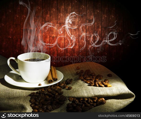 Steaming cup of coffee, cinnamon sticks and a few coffee beans. still life