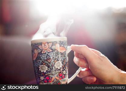 Steaming tea cup and sunlight, warm-up in winter