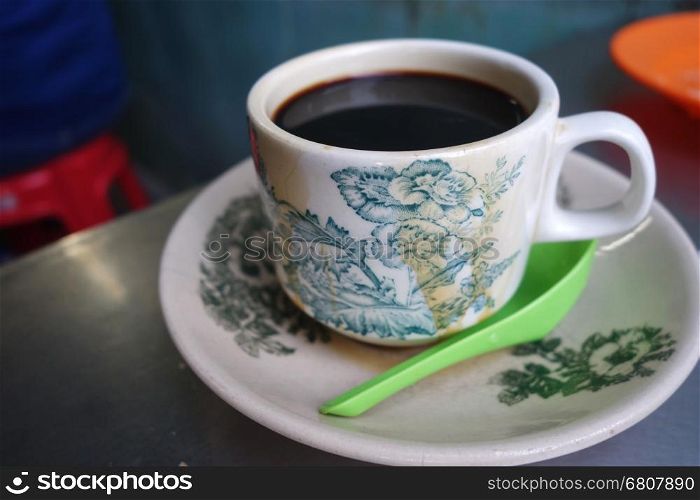 Steaming traditional oriental Chinese kopitiam style dark coffee in vintage mug and saucer