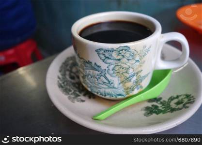 Steaming traditional oriental Chinese kopitiam style dark coffee in vintage mug and saucer