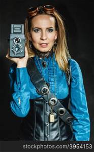 Steampunk with old retro camera.. Photography and retro style. Young vintage attractive girl holds old aged camera. Steampunk photographer taking photo.