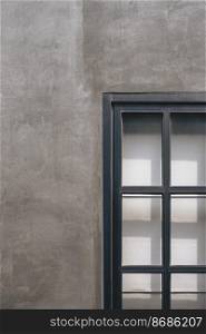 Steel and glass window on gray concrete loft wall of vintage house in vertical frame with sunlight and shadow on surface
