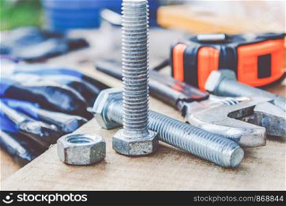 Steel bolt nuts and washers lie on wooden boards near an adjustable spanner and a tape measure. The concept of tools and repair work.. Steel bolt nuts and washers lie on wooden boards near an adjustable spanner and a tape measure.