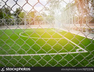 Steel cage foreground with green grass sport outdoor Football field - Futsal field