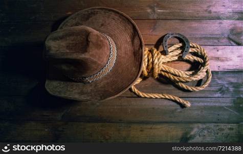 steel classic horseshoe cowboy hat and coarse rope on a dark wooden background top view. Horse Shoe Hat