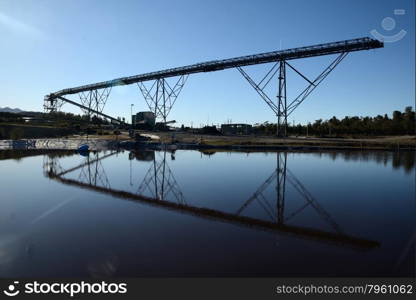 Steel infrastructure for loadout facilities reflected in a storage pond at a coal mine