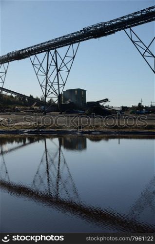Steel infrastructure for loadout facilities reflected in a storage pond at a coal mine