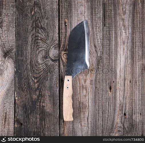 steel knife for cutting meat with a wooden handle on a gray background from old boards, top view