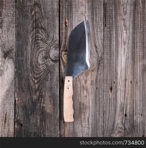 steel knife for cutting meat with a wooden handle on a gray background from old boards, top view