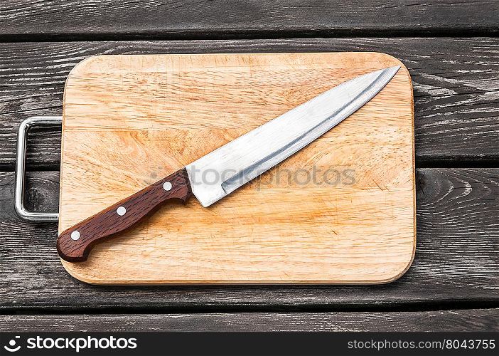 Steel knife on a cutting board on wooden background with. Steel knife on a cutting board wooden background with