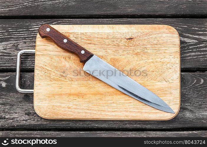 Steel knife on a cutting board wooden background with. Steel knife on a cutting board on wooden background with