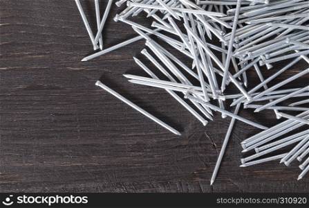 Steel nails scattered on a black old wooden plank. steel nails