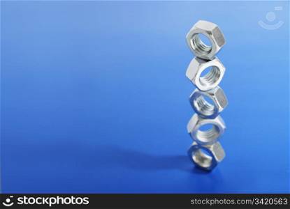 Steel nuts stacked on blue background.