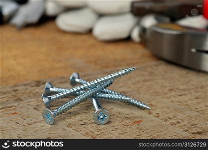 steel screws and different tools on wooden background.