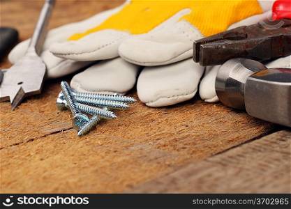 steel screws and different tools on wooden background.